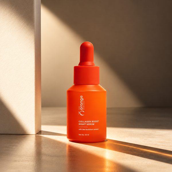 An orange dropper bottle of The Orange Collagen Boost Night Serum, set on a reflective surface with dramatic warm sunlight and shadows.